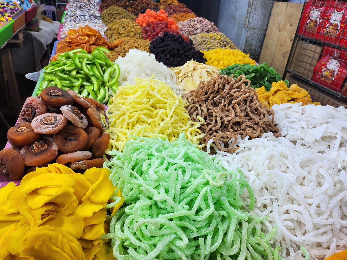 Các loại mứt Tết màu sắc sặc sỡ, không được bảo quản, che đậy bày trên sạp hàng tại phố Hàng Buồm, Hà Nội. Ảnh Trịnh Anh