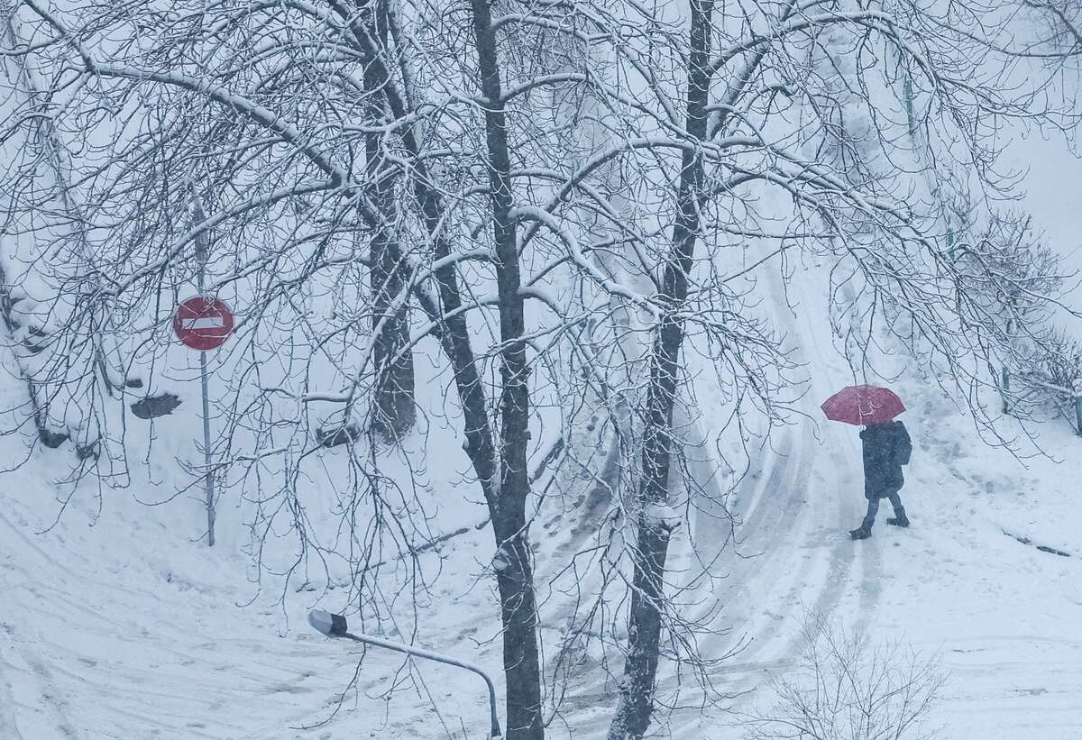 Một người cầm ô đi trên đường khi tuyết rơi ở Kiev, Ukraine, ngày 1/12. (Ảnh: Reuters)