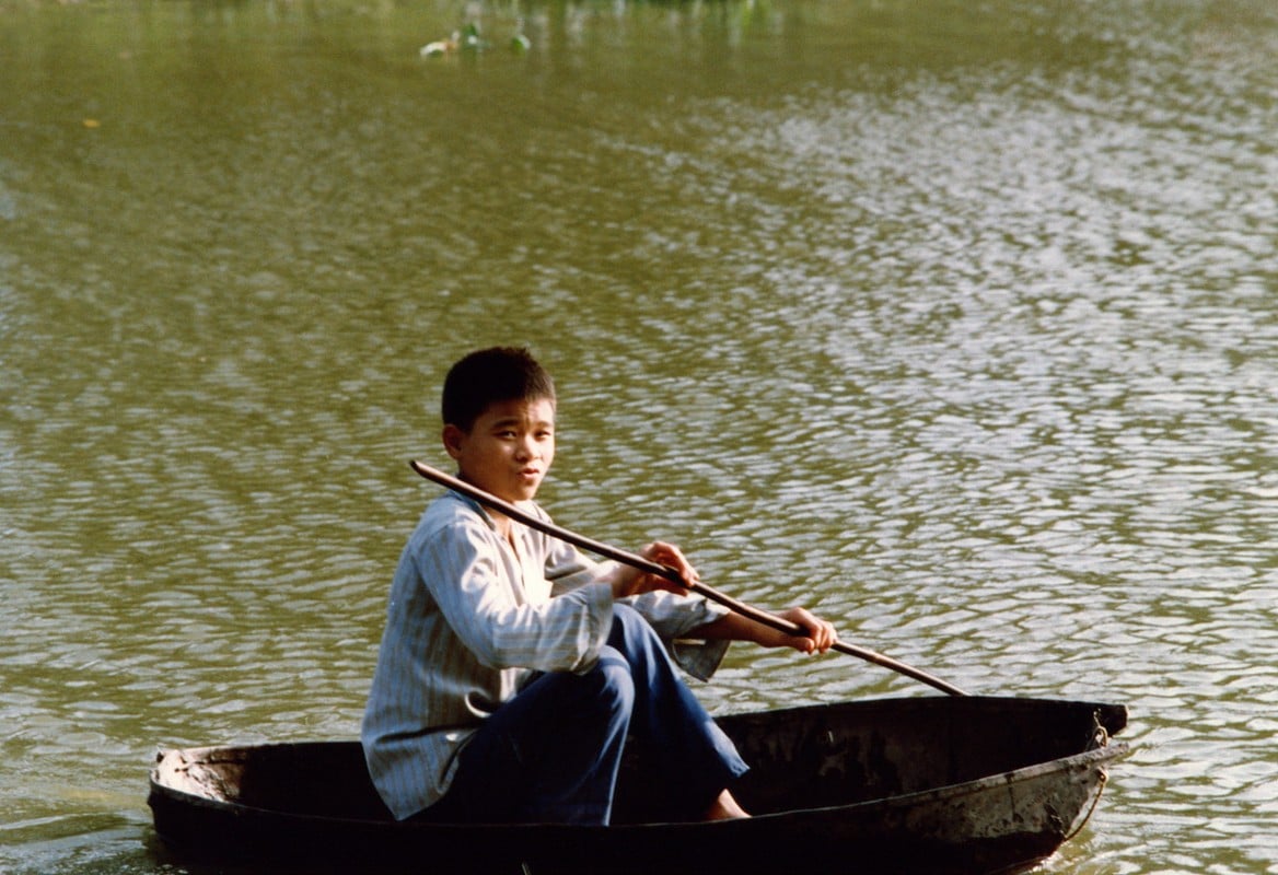 Một cậu bé chèo thuyền thúng trên hồ.